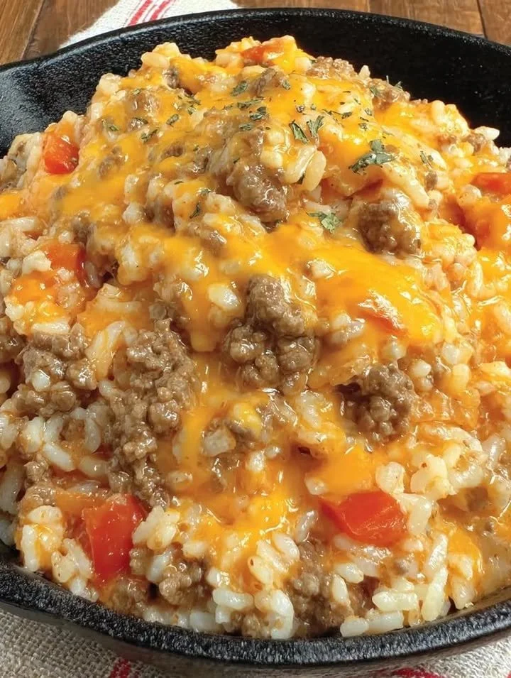 Cheesy queso ground beef rice served in a bowl, topped with fresh herbs.