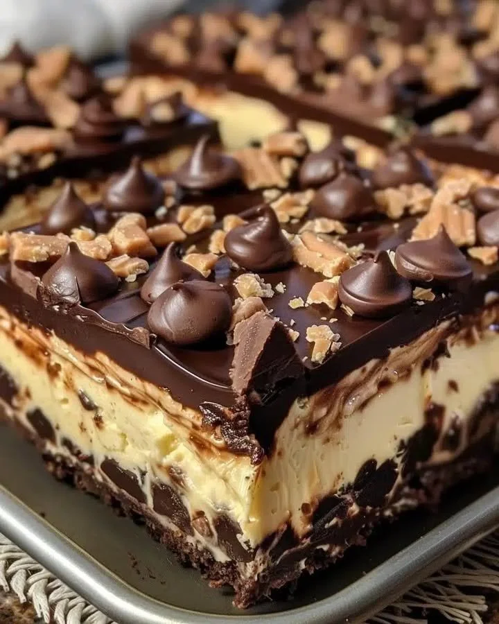 Delicious Reese's Butterfinger cheesecake bars topped with chocolate and caramel.