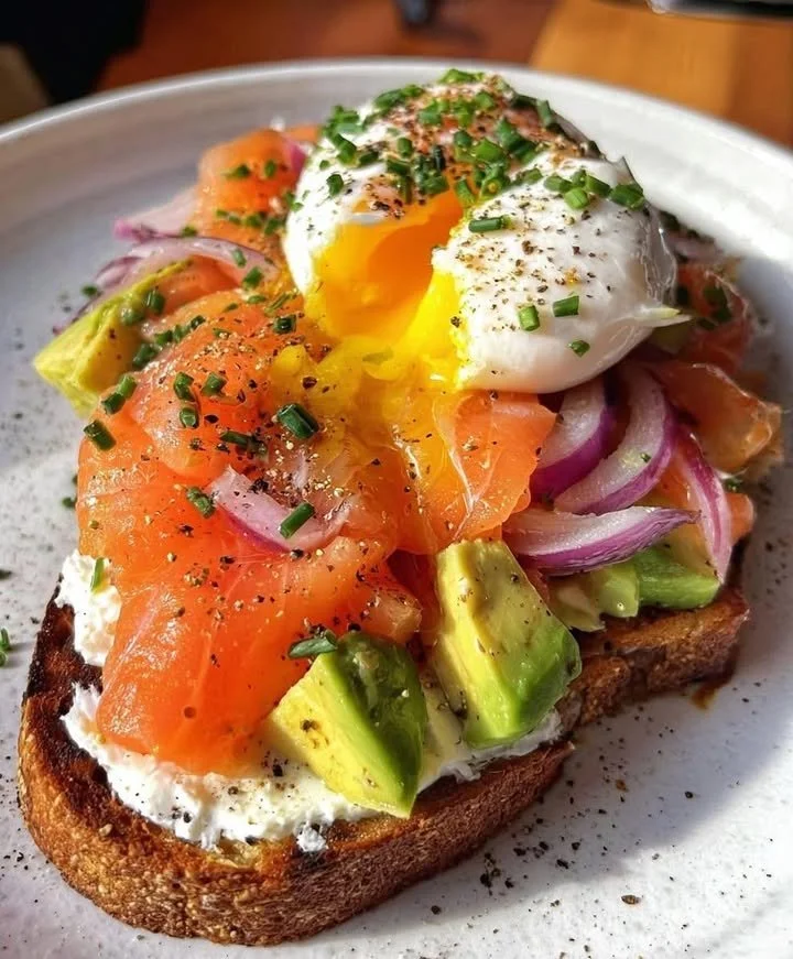 Smoked salmon toast with avocado, poached egg, and cream cheese on a plate.