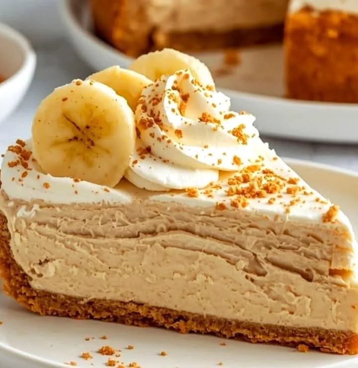 Slice of classic banana cream cheesecake garnished with banana slices and whipped cream.