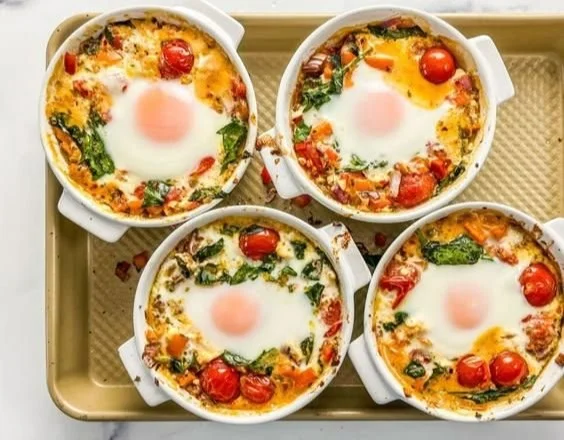 Baked feta eggs with tomatoes and spinach served in a rustic dish