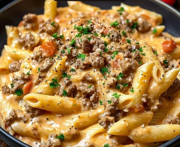 Creamy beef pasta dish served in a bowl with herbs on top