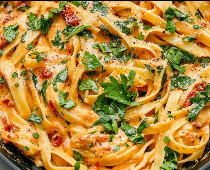 Creamy vegan sun-dried tomato pasta garnished with fresh herbs