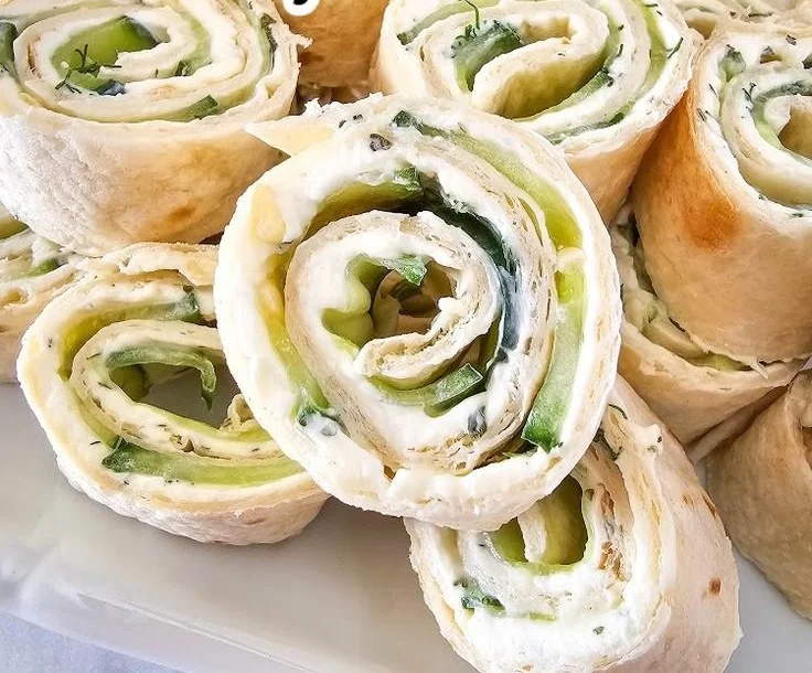 Cucumber Dill Pinwheels arranged on a platter as a refreshing appetizer.