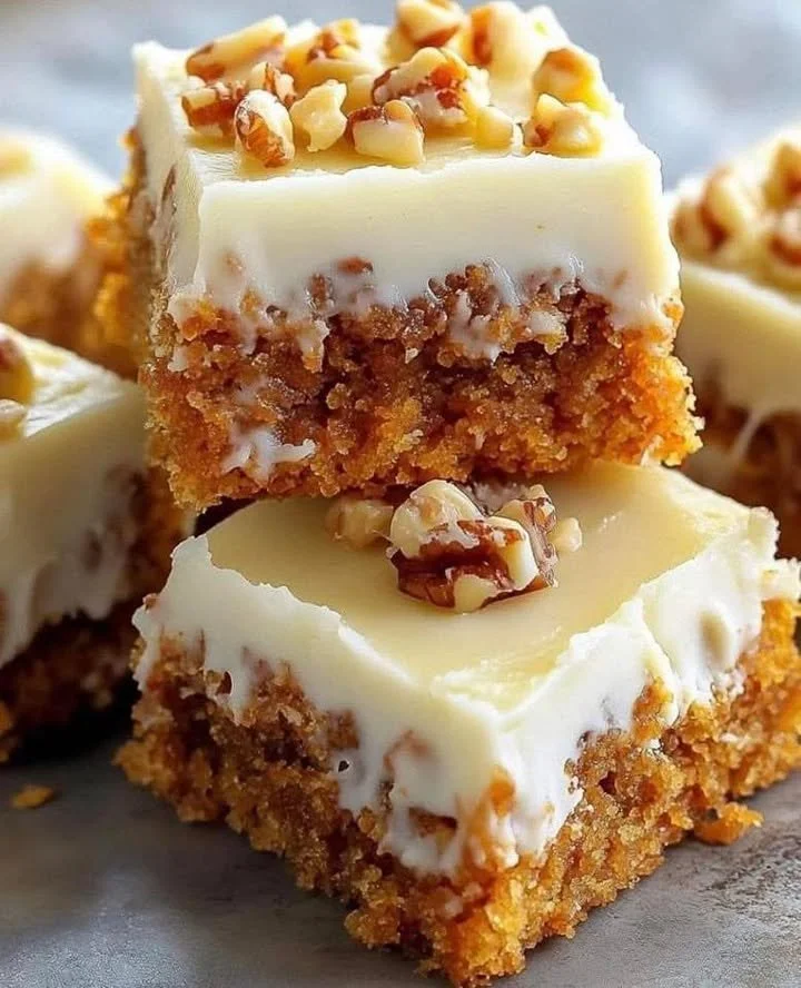 Decadent carrot cake bars with cream cheese frosting on white plate
