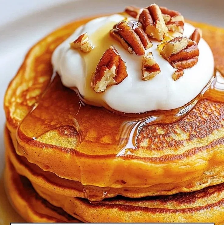 Fluffy sweet potato pancakes stacked on a plate with syrup and berries