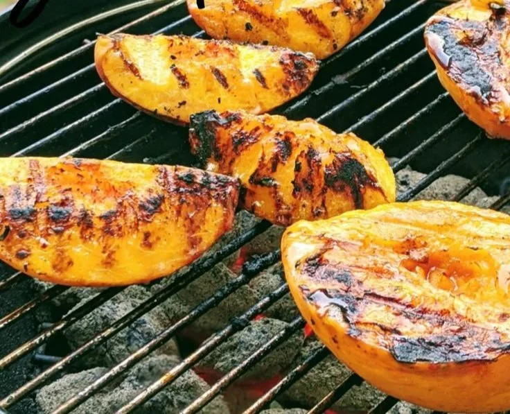 Delicious grilled peaches served on a plate, perfect for summer desserts.