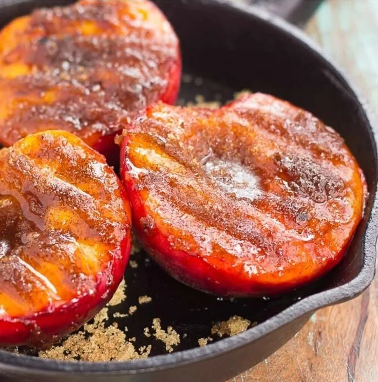 Grilled peaches topped with cinnamon and brown sugar on a plate