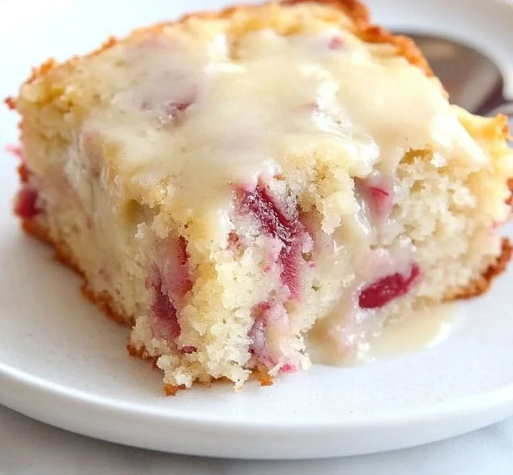 Delicious Moist Rhubarb Cake with Butter Sauce on a white plate.