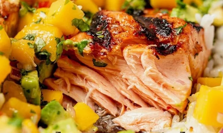 Grilled salmon topped with fresh mango salsa on a plate