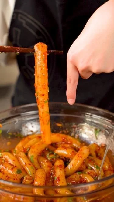 A plate of spicy potato noodles garnished with fresh herbs and chili flakes