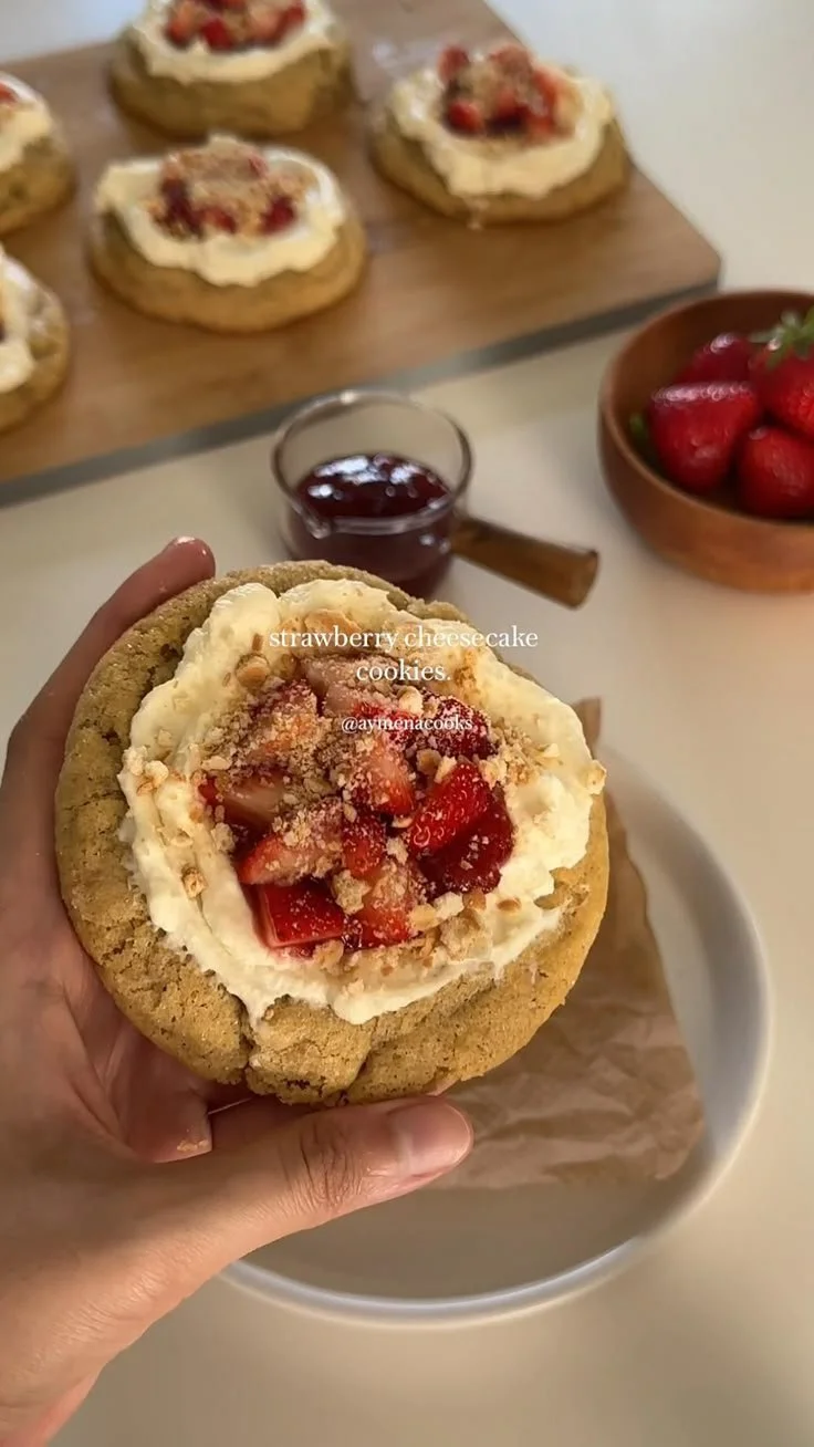 Delicious strawberry cheesecake cookies topped with fresh strawberries and cream.