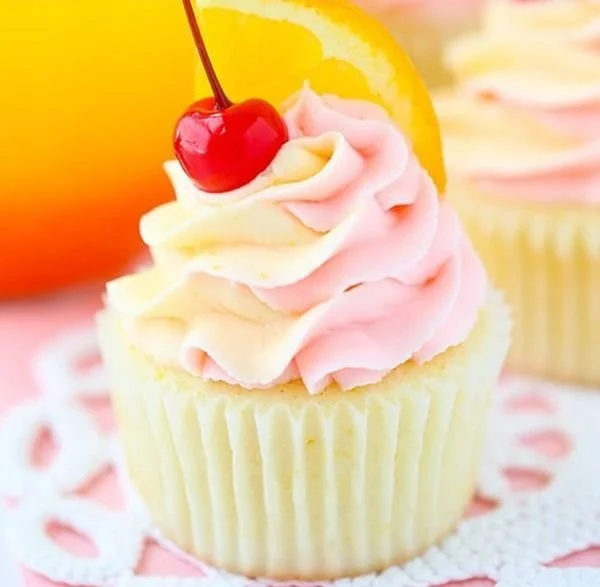 Delicious Tequila Sunrise Cupcakes with vibrant colors and garnished with orange and cherry.