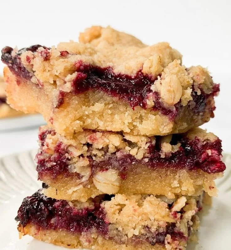 Vegan berry crumble bars topped with oats and berries on a white plate